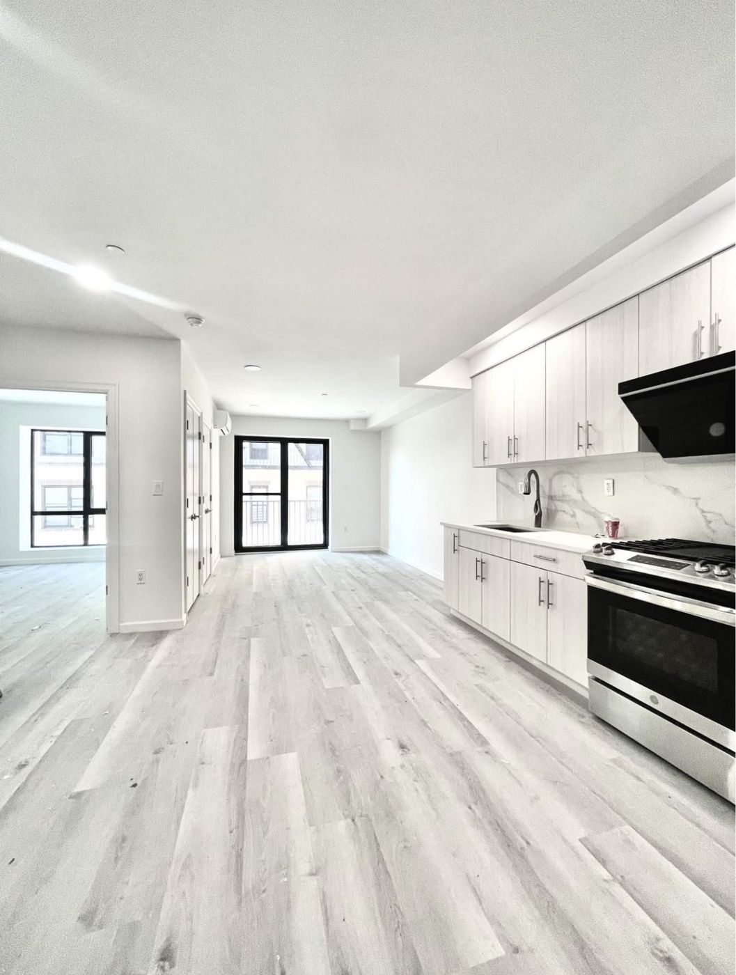 Renovated kitchen with gas range, stainless appliances, marble backsplash, and black-framed balcony doors